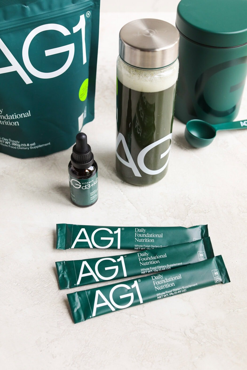 Overhead view of a variety of different AG1 products and packaging on a marble countertop. 