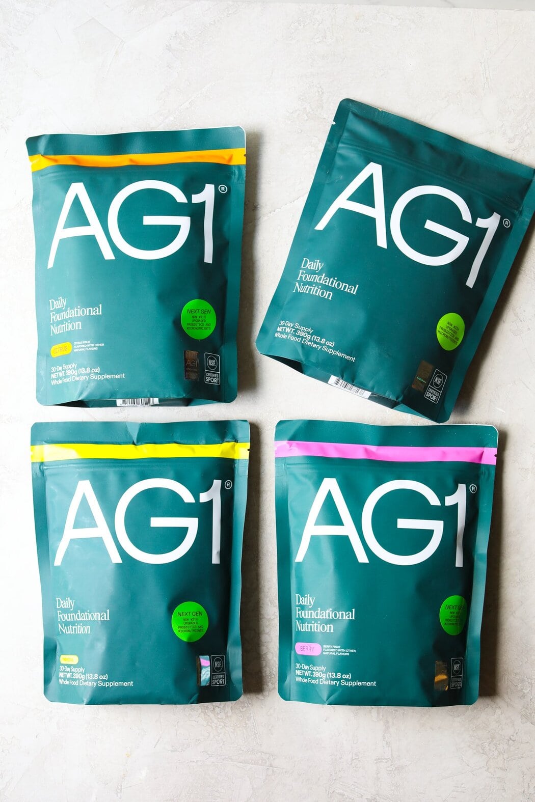 Overhead view of several bags of AG1 powdered greens in a variety of flavors including citrus. 