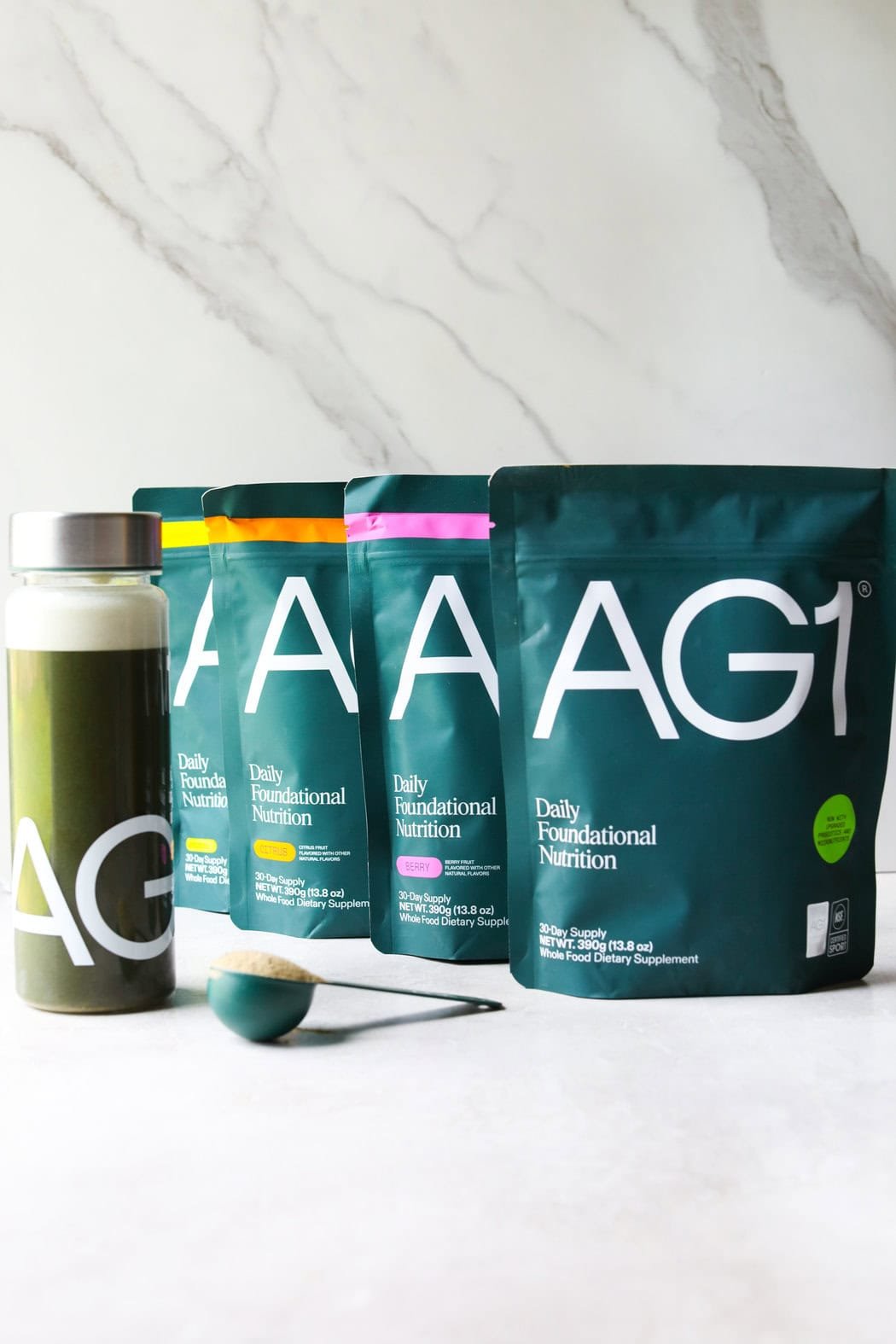 Close up view of several bags of AG1 greens powder in bags with a variety of flavor options including citrus. 
