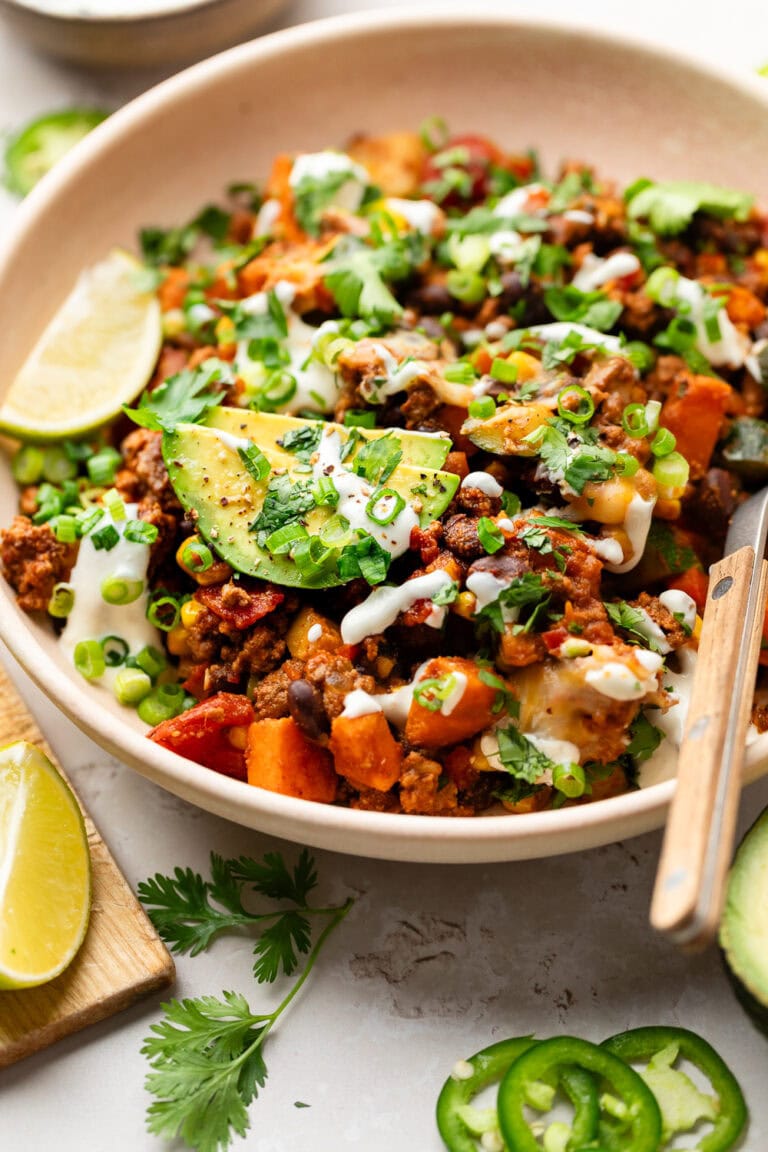 Close up view of a plate filled with ground beef and zucchini skillet garnished with avocado and cilantro.