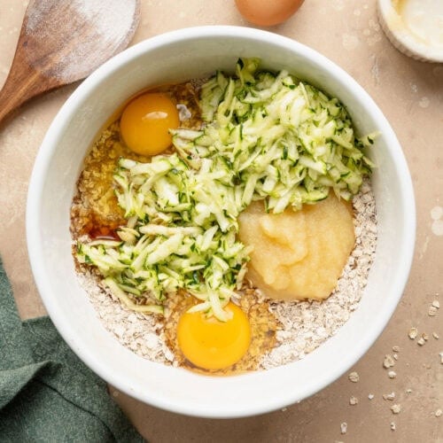 A bowl of shredded zucchini, eggs, and flavor enhancers.