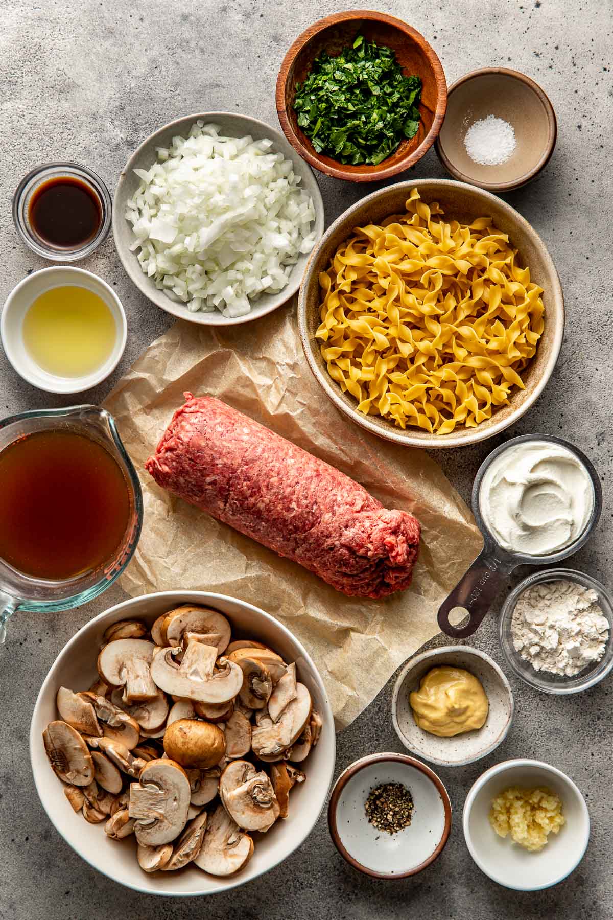 Overhead view of a variety of ingredients for ground beef stroganoff in different sized bowls. 