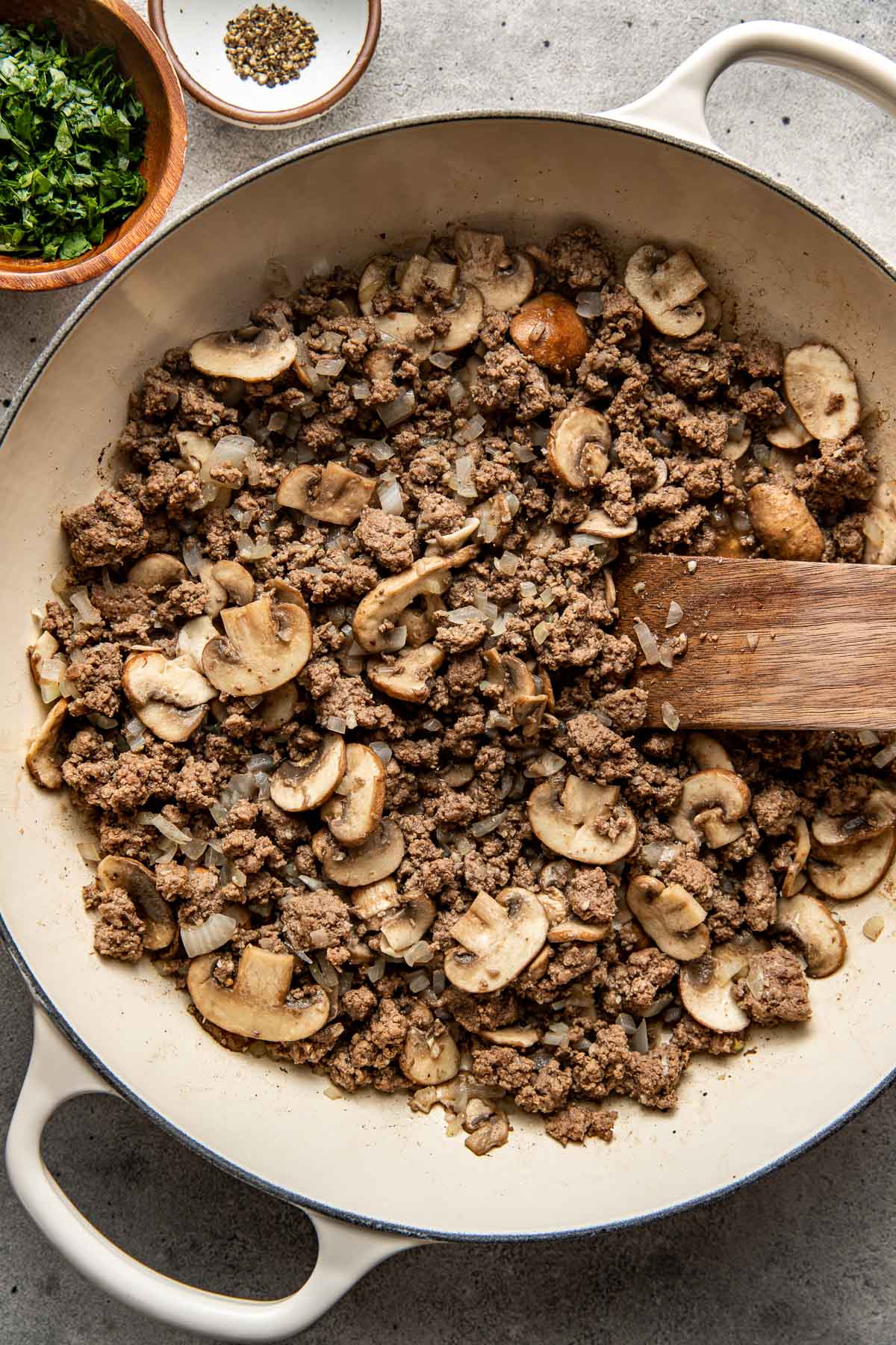 Overhead view of a pan of ground beef stroganoff cooking with mushroom pieces and ground beef. 
