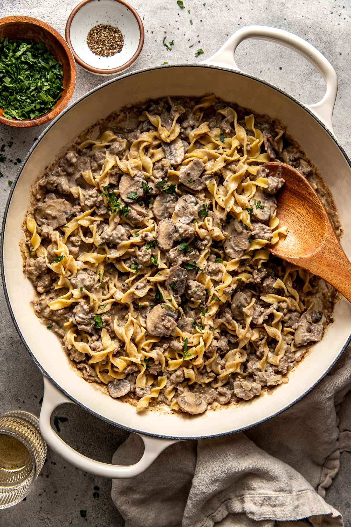 Overhead view of a cast iron pan filled with ground beef stroganoff topped with fresh herbs. 