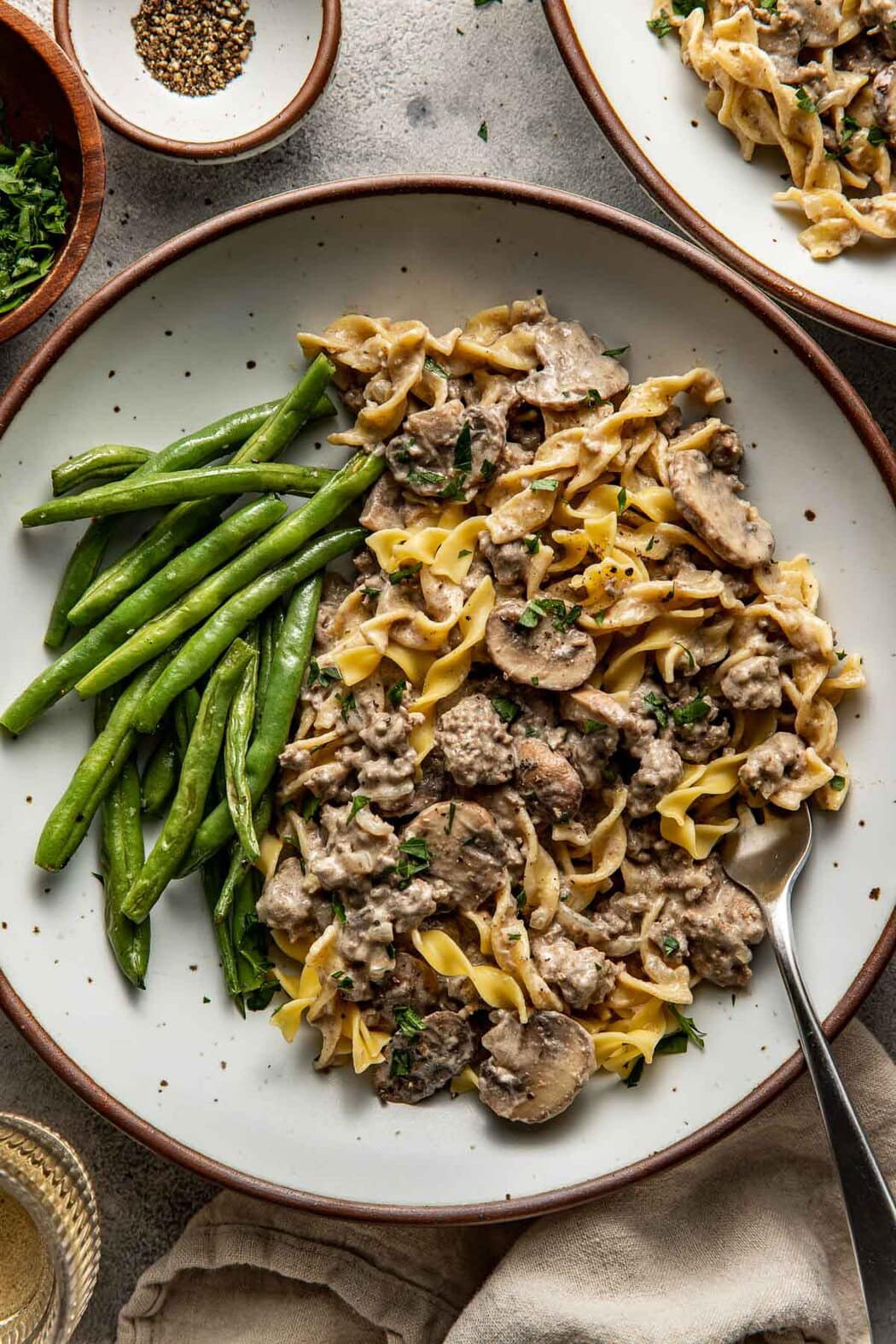 Close up view of a plate of Easy and Delicious Ground Beef Stroganoff with green beans on the side. 