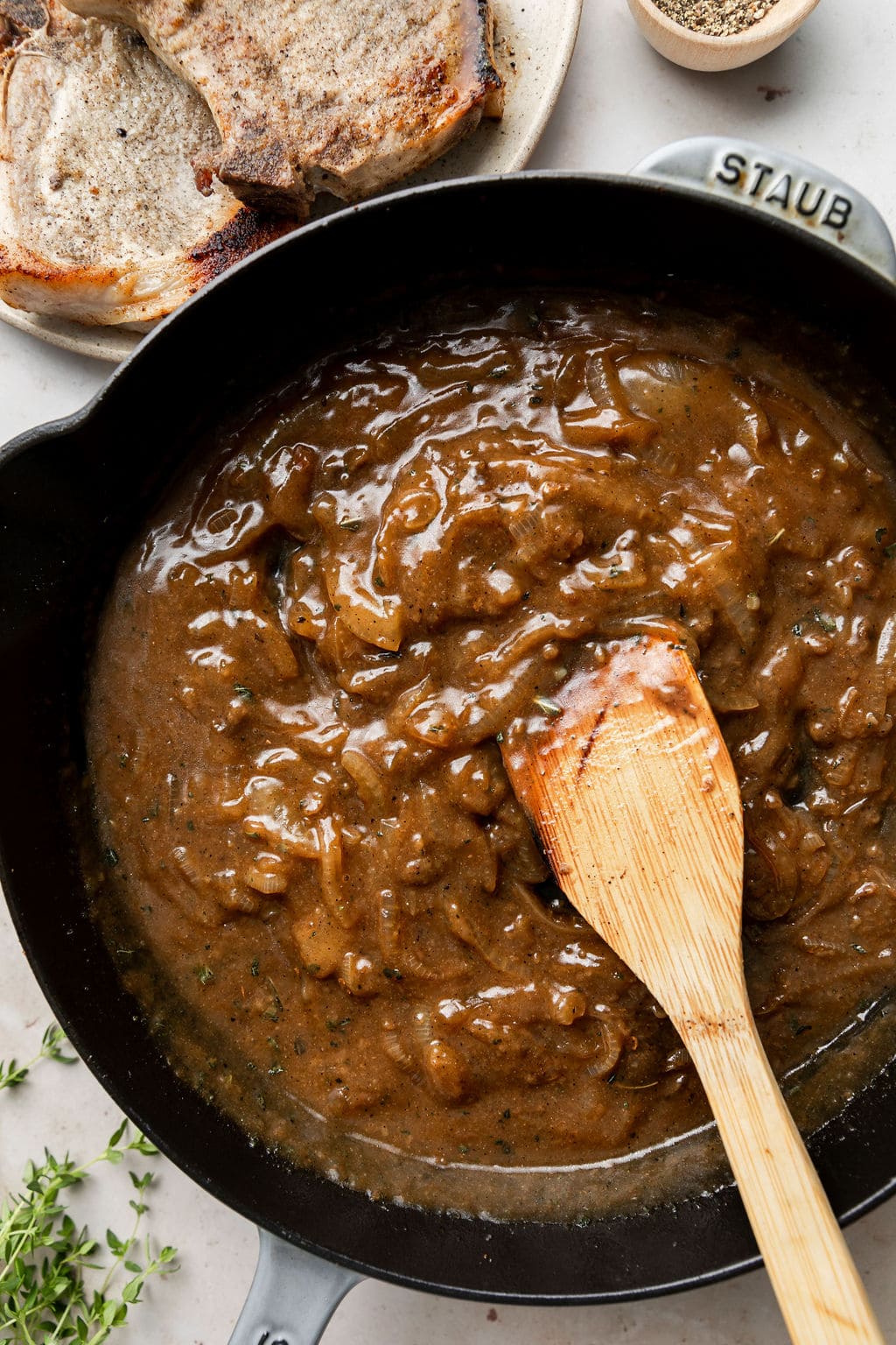 Overhead view of a cast iron skillet filled with brown gravy mixture for The Best Smothered Pork Chops.