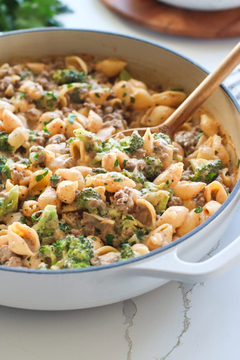 Close up view of a skillet filled with creamy homemade hamburger helper topped with black pepper and fresh herbs in a creamy sauce. 