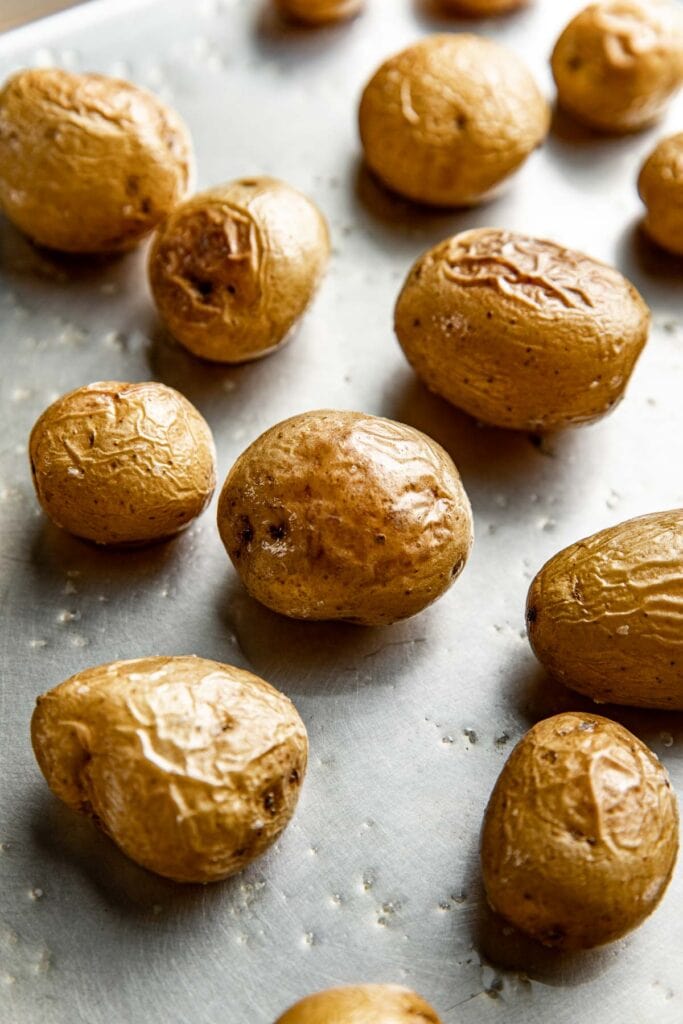 Close up view of Roasted Baby Potatoes on a sheet pan topped with flakey sea salt. 