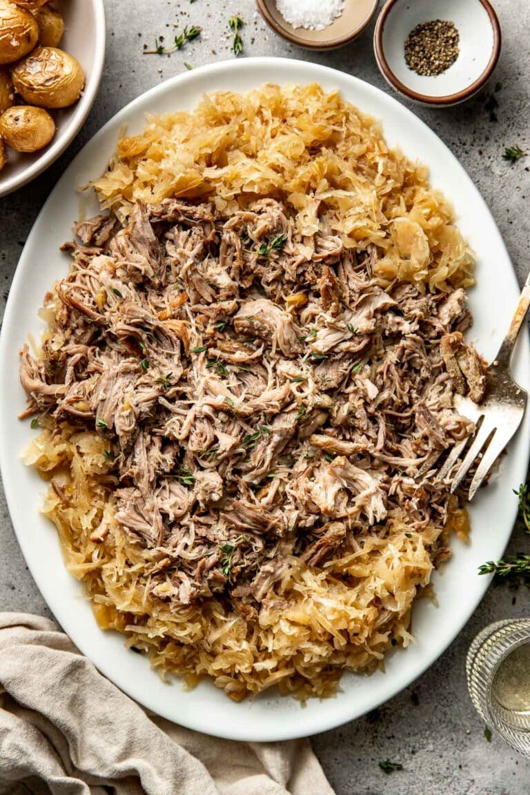 Overhead view of a platter filled with shredded pork and surrounded by sauerkraut. 