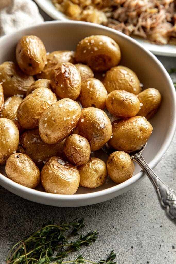 Close up view of a bowl of Roasted Baby Potatoes topped with flakey sea salt. 