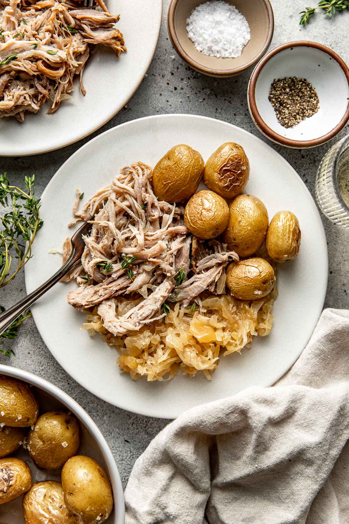 Overhead view of a plate of freshy cooked Pork and Sauerkraut with a side of roasted potatoes. 