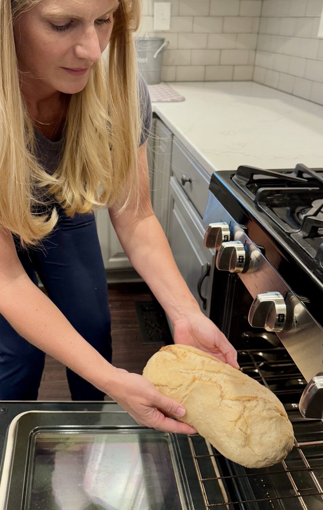 Close up view of a woman putting a loaf of sourdough into an oven.