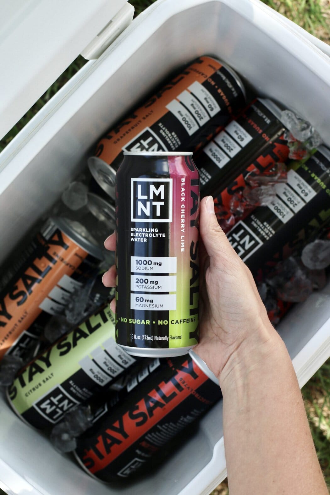 Overhead view of a hand grabbing a can of LMNT sparking electrolyte water. 