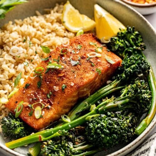 A piece of salmon on a bed of quinoa with roasted broccolini