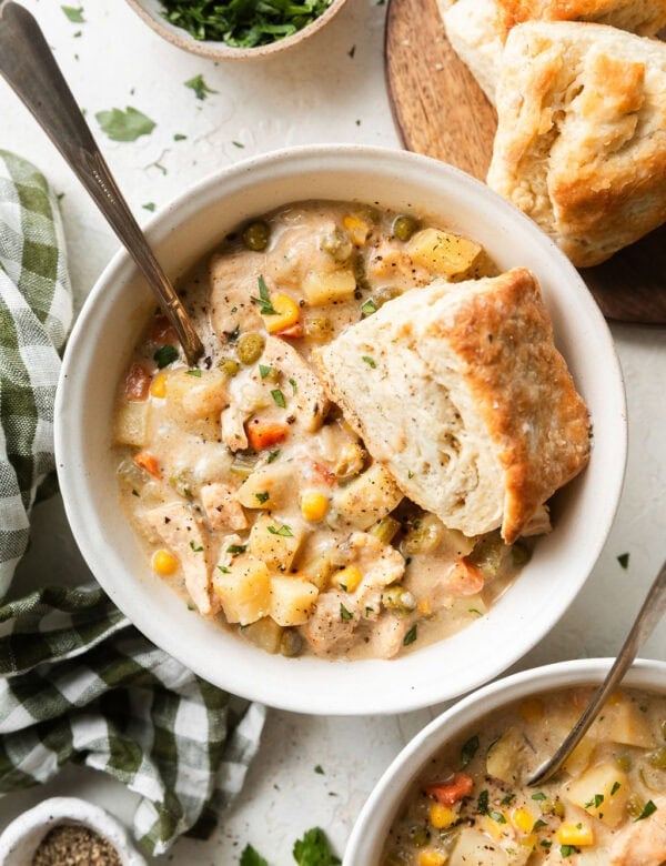 Overhead view pot pie soup in a white bowl, homemade biscuit on top of soup