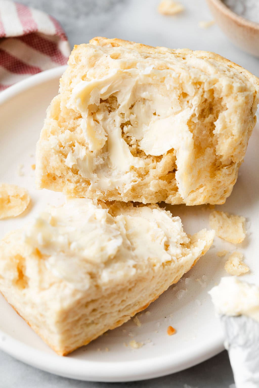 Close up view of a freshly cut biscuit with melty butter on it. 
