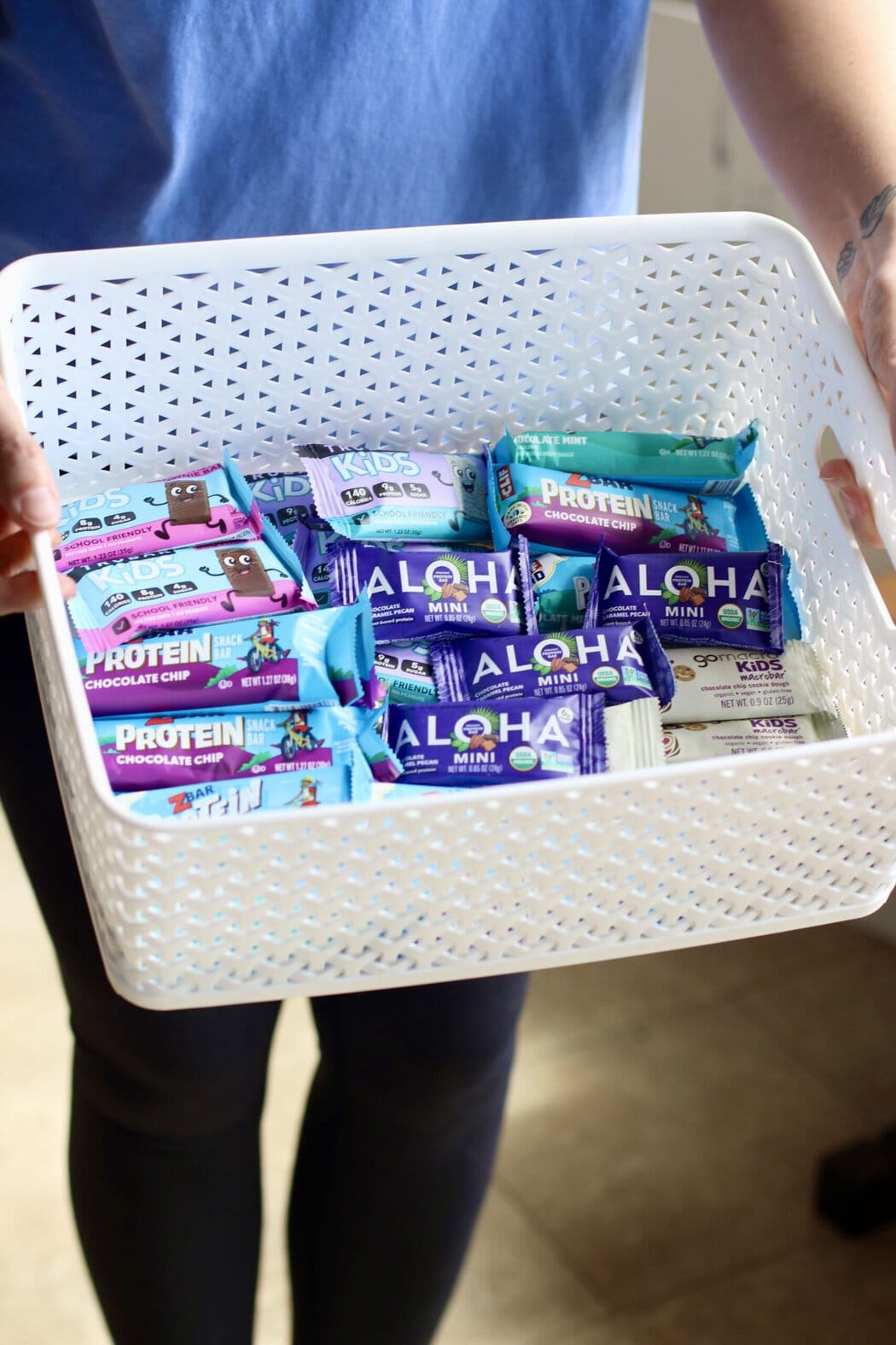 Overhead view of someone holding a white basket filled with kids' protein bars.