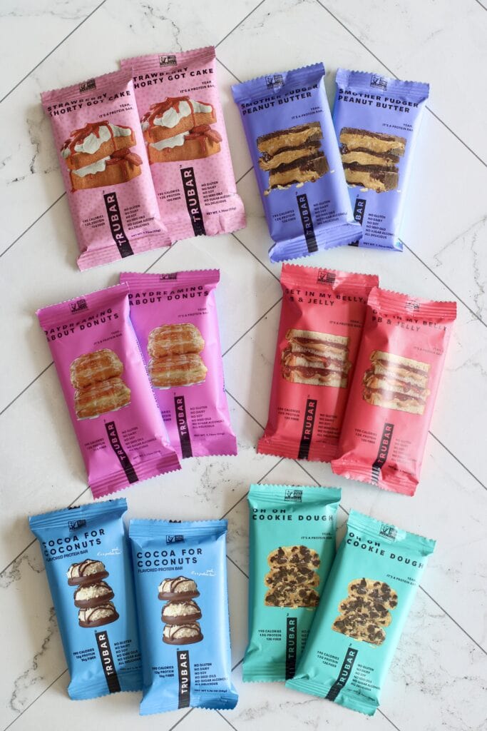 Overhead view of a variety of Trubars arranged on a white marble countertop.