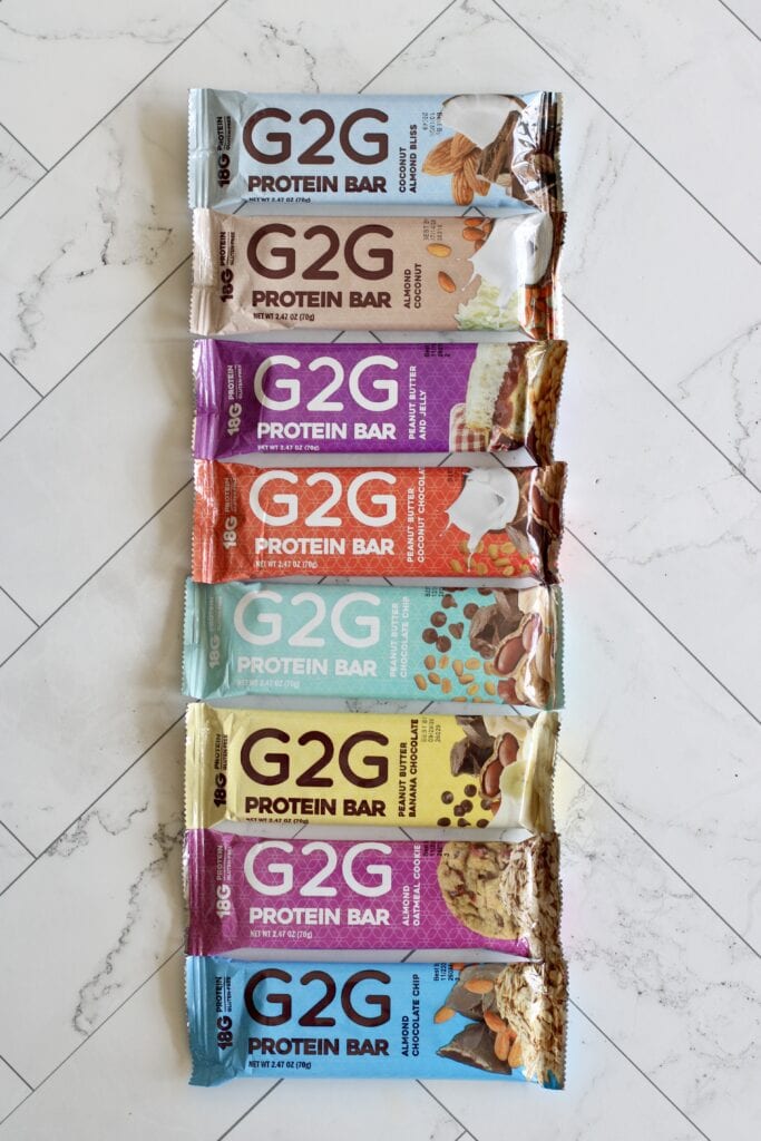 Overhead view of a line of G2G protein bars on a marble countertop.