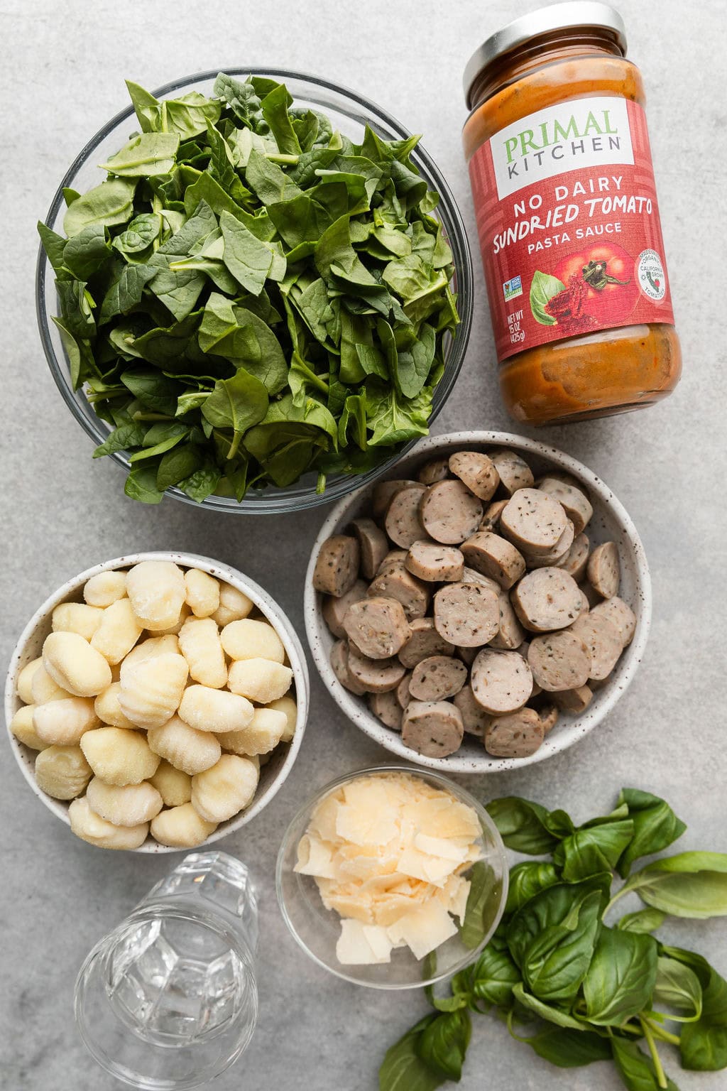 Overhead view of a variety of ingredients for Sausage And Gnocchi Skillet in different sized bowls. 