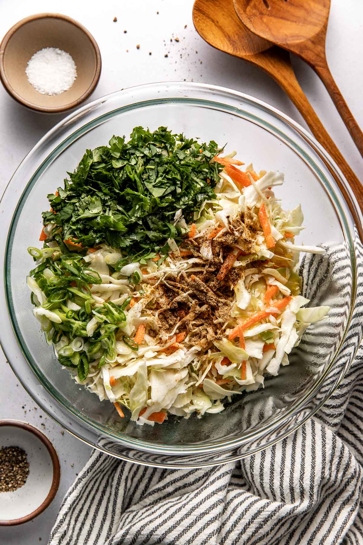 Overhead view of a glass bowl filled with Cilantro Lime Slaw ingredients ready for stirring. 