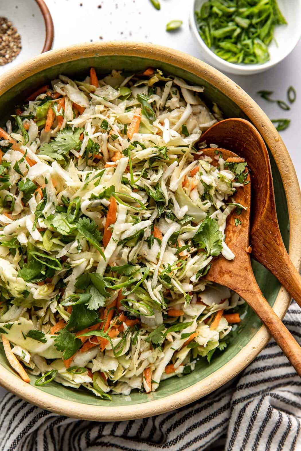 Overhead view of a bowl of fresh Cilantro Lime Slaw topped with green onions. 