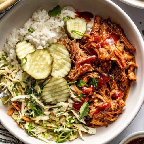 Overhead view of a Crockpot Pulled Pork Bowl topped with sliced dill pickles and green onions.