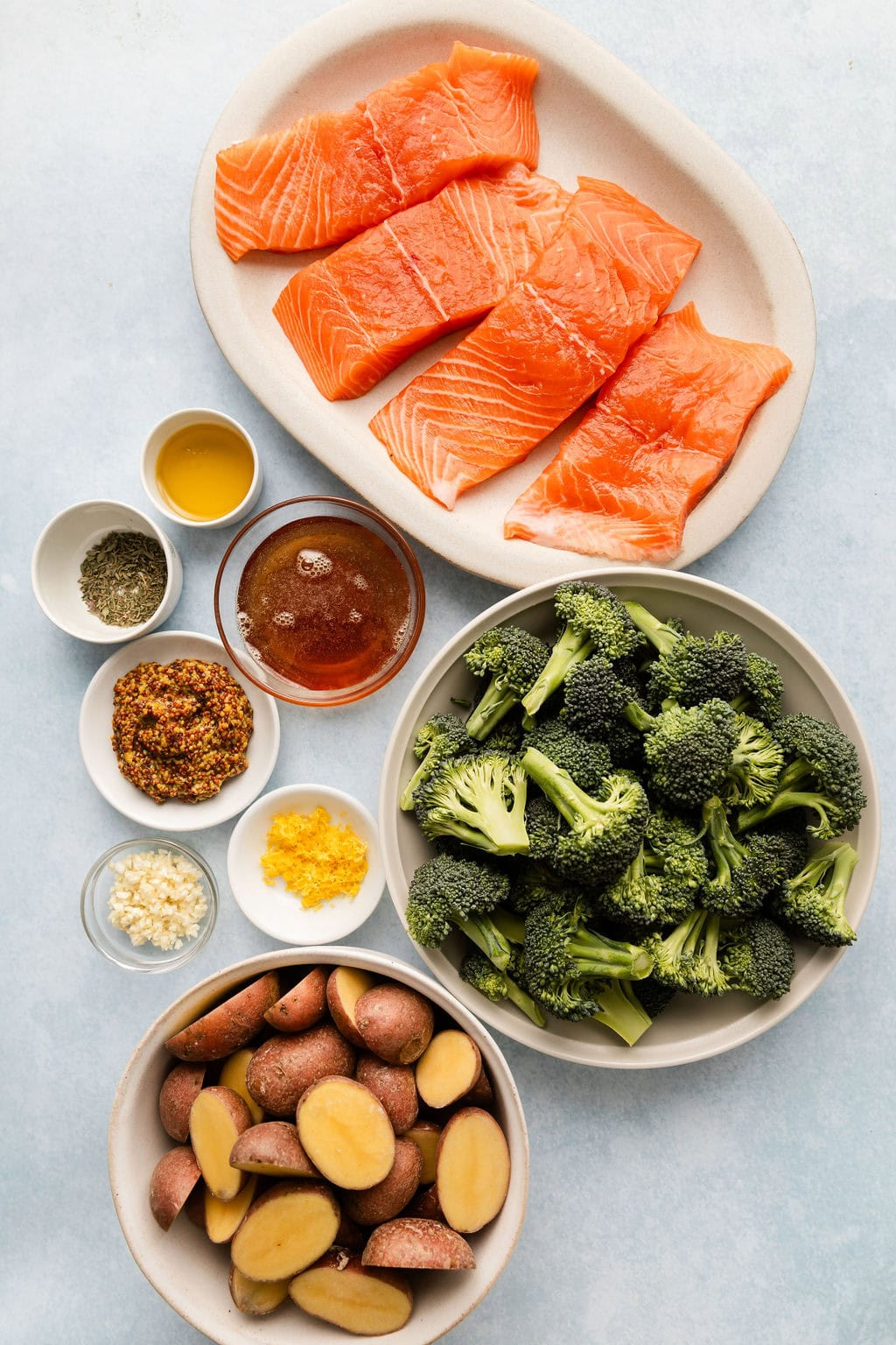 Overhead view of a variety of ingredients for Sheet Pan Honey Mustard Salmon in different sized bowls