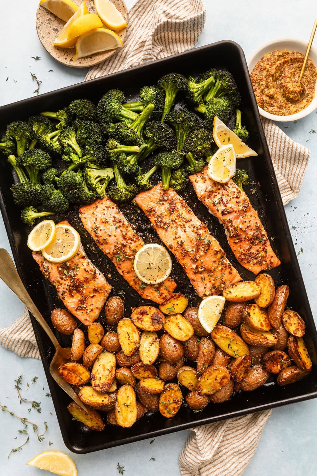 Close up view of Sheet Pan Honey Mustard Salmon on a sheet pan topped with lemon slices