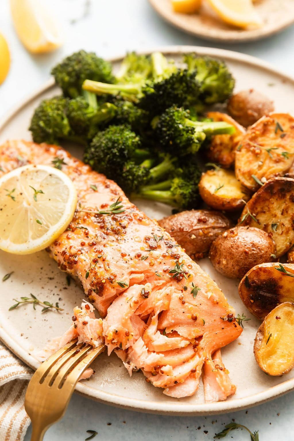 Close up view of a plate of Sheet Pan Honey Mustard Salmon with roasted potatoes and broccoli