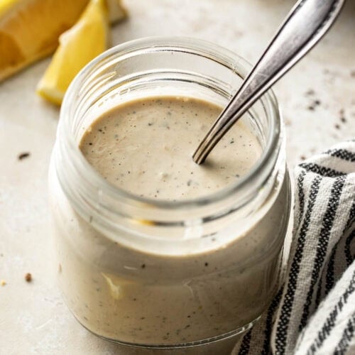 A glass jar of Homemade Caesar Dressing with a spoon in it