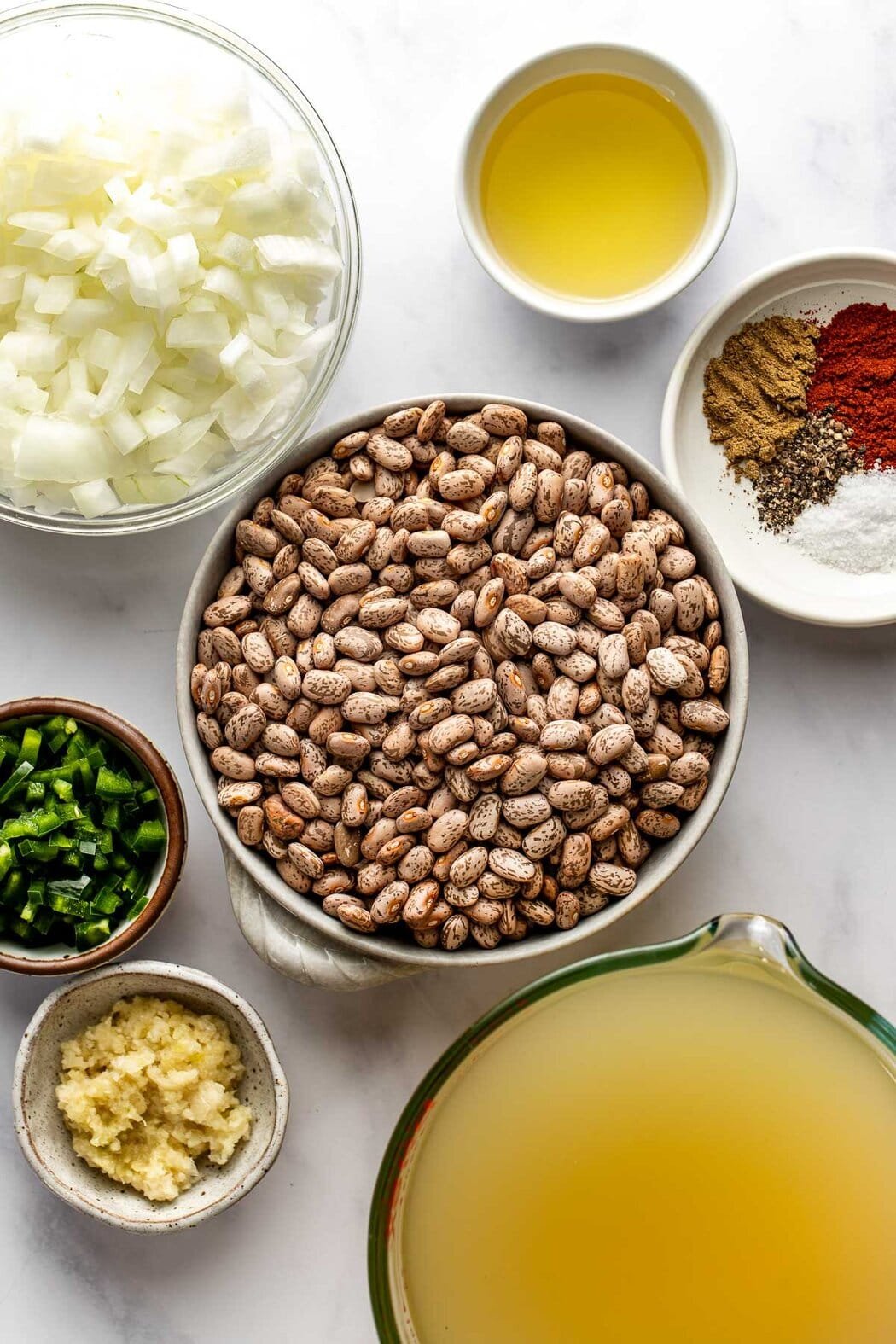 Overhead view of a variety of ingredients for refried beans in different sized bowls.