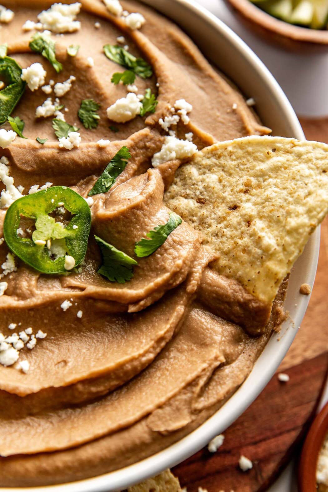 Close up view of a bowl of refried beans with a chip stuck in the side