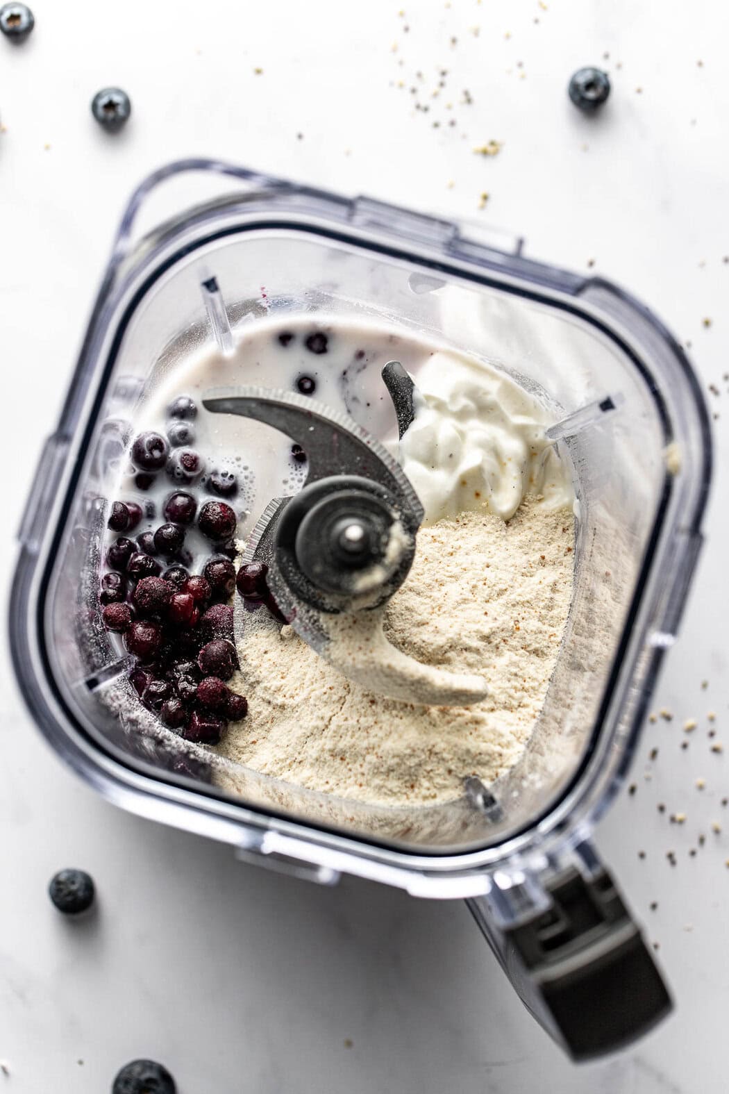 Overhead view of a blender filled with Post Workout Smoothie ingredients including frozen blueberries