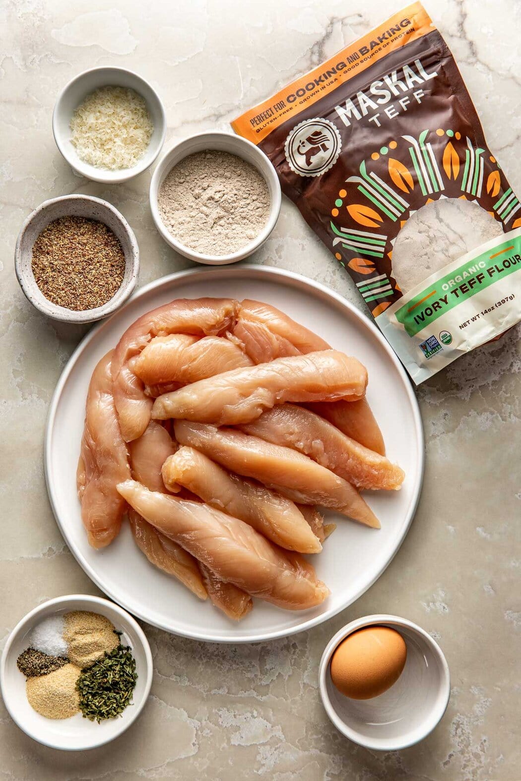 Overhead view of a variety of ingredients for Air Fryer Chicken Tenders in different sized bowls.