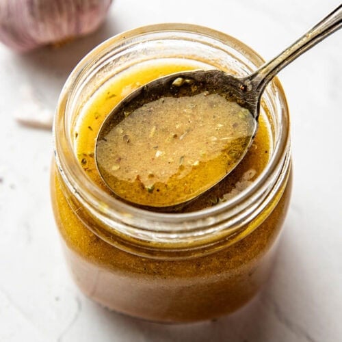 Close up view of a jar of Red Wine Vinaigrette with a spoon bringing up a scoop showing the texture.
