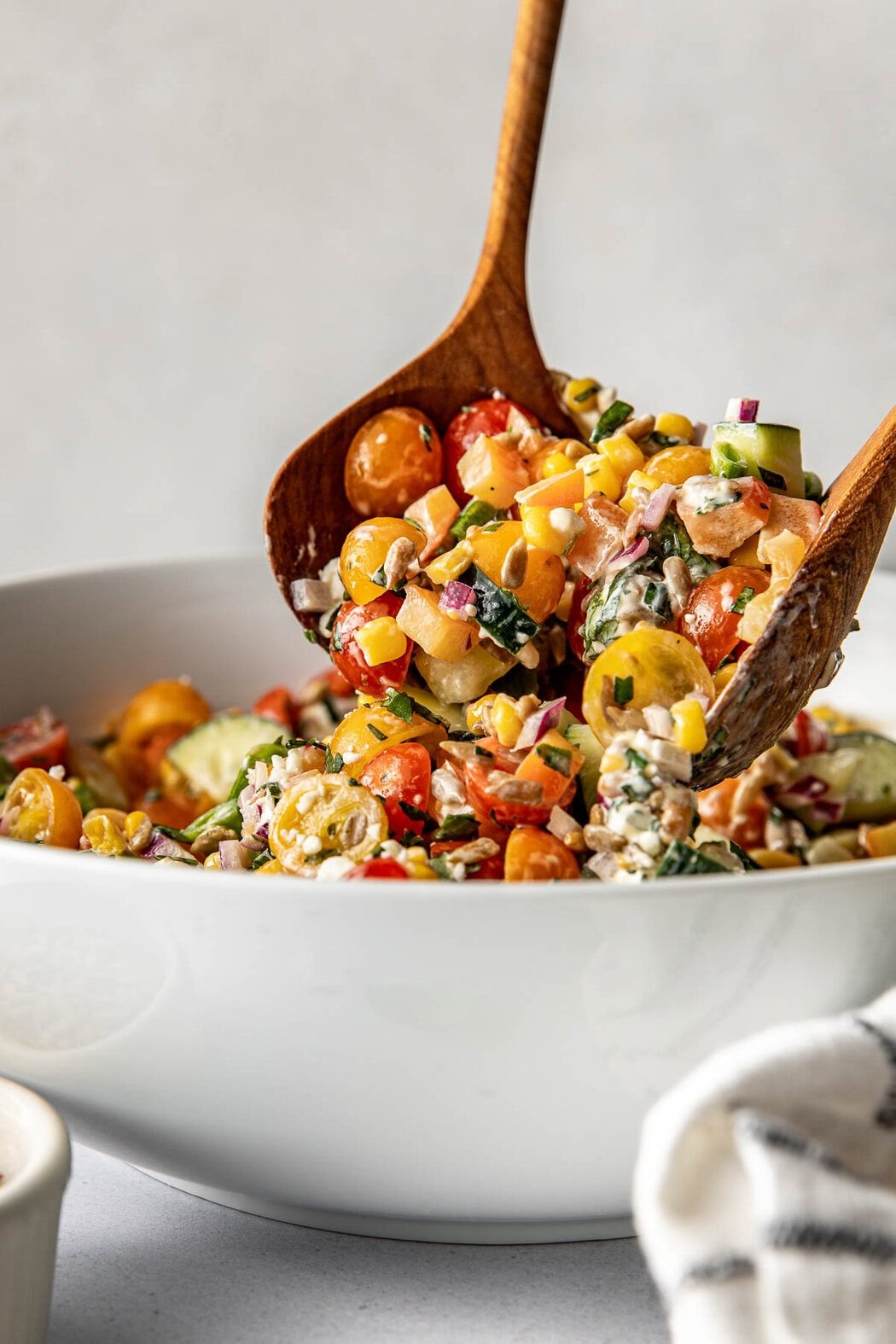 Close up view of two wooden spoons scooping up colorful summer salad showing the texture of the variety of vegetables   