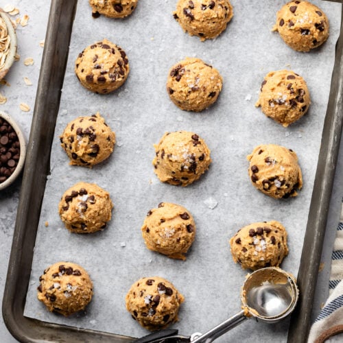Overhead view of a sheet pan lined with parchment paper and filled with cookie dough bites.