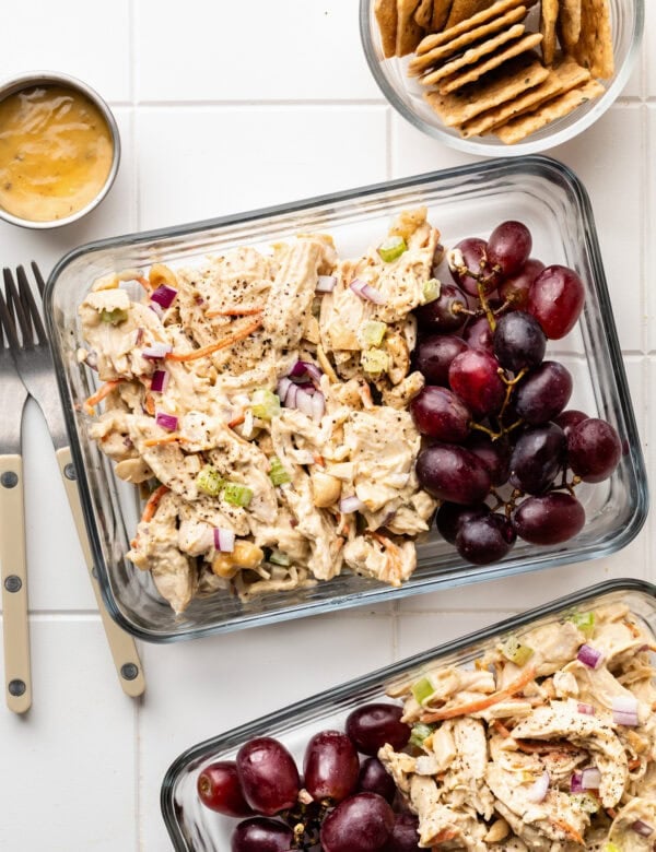 Overhead view meal prep containers filled with honey mustard chicken salad and red grapes