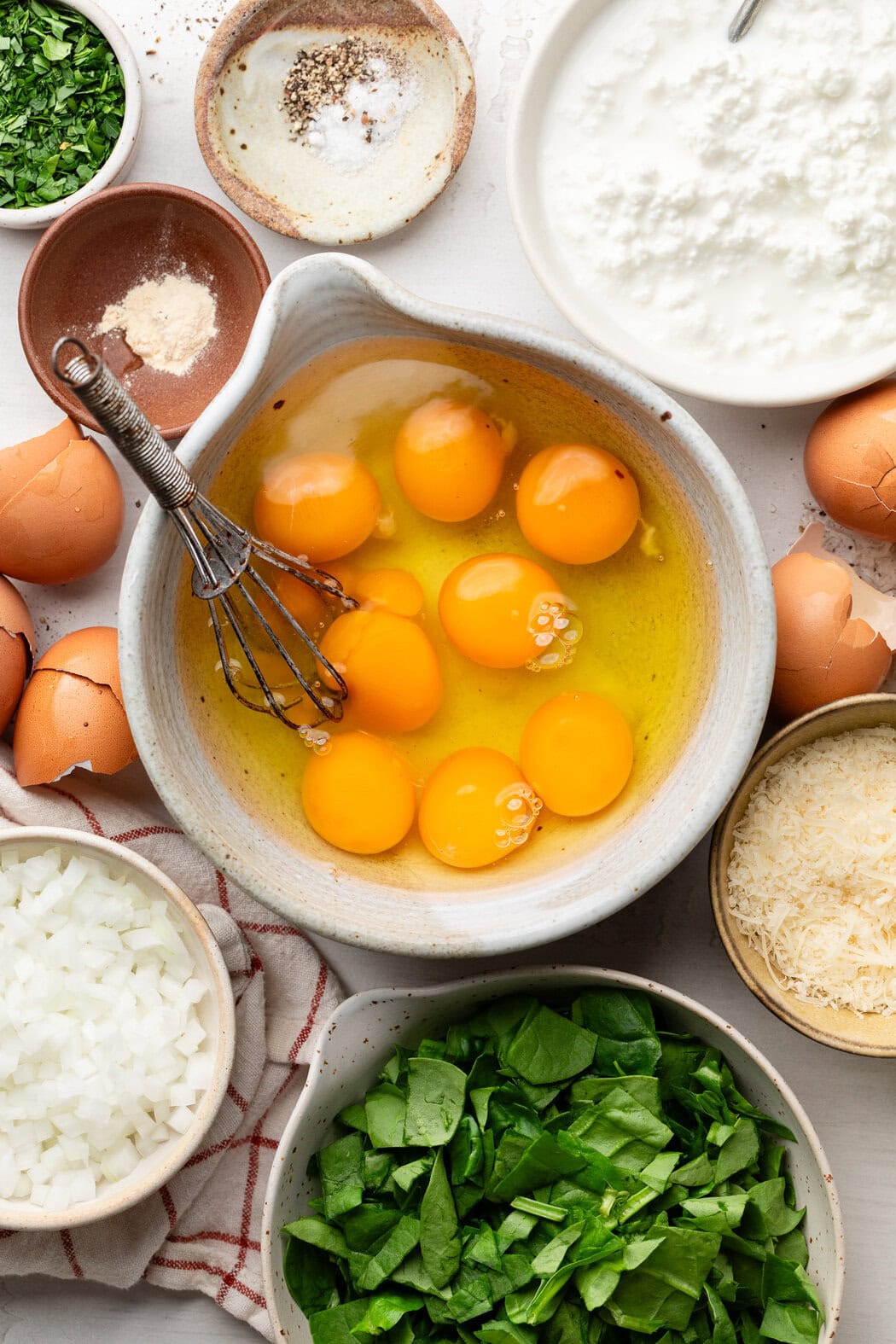 Overhead view of a variety of ingredients for Cottage Cheese Egg Bake in different sized bowls. 