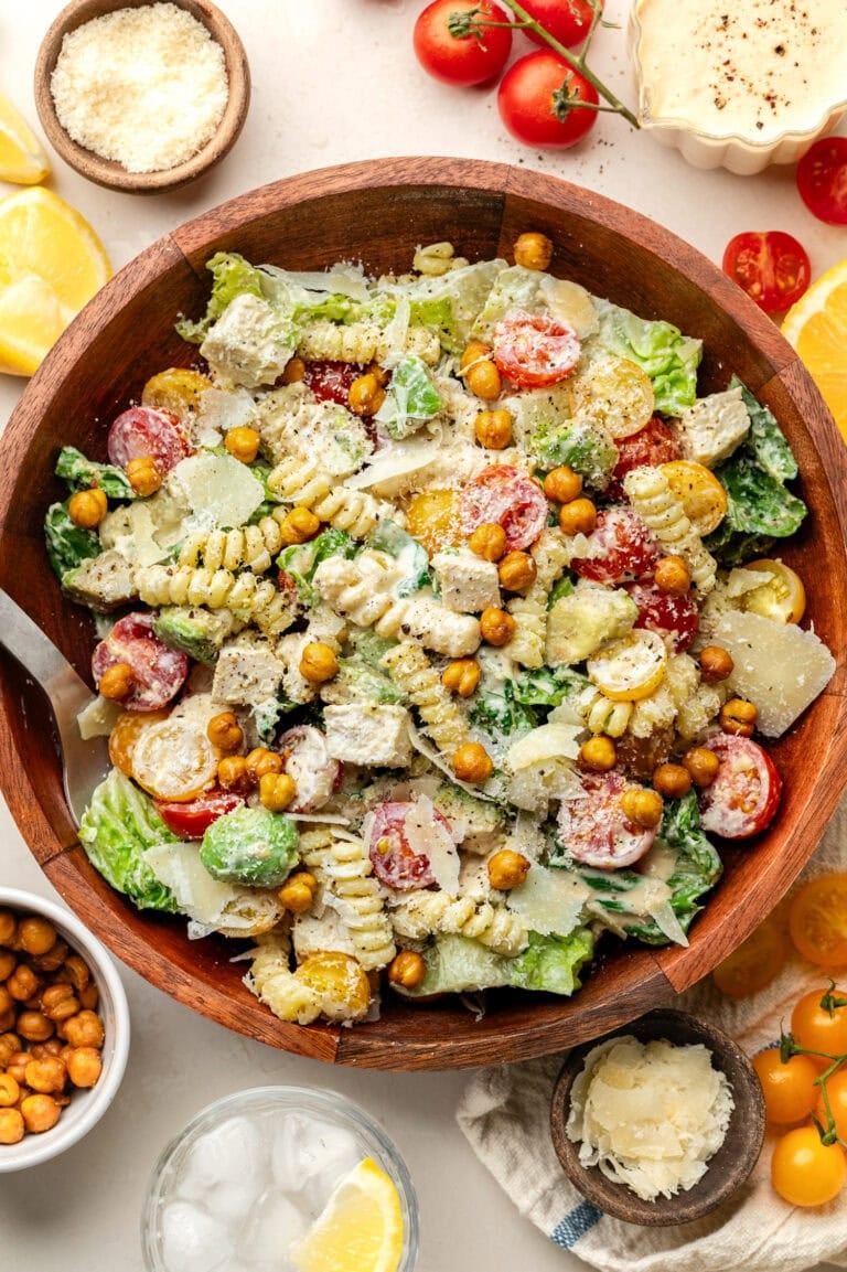 Overhead view of a large serving bowl filled with Chicken Caesar Pasta Salad topped with grated parmesan cheese and roasted chickpeas.