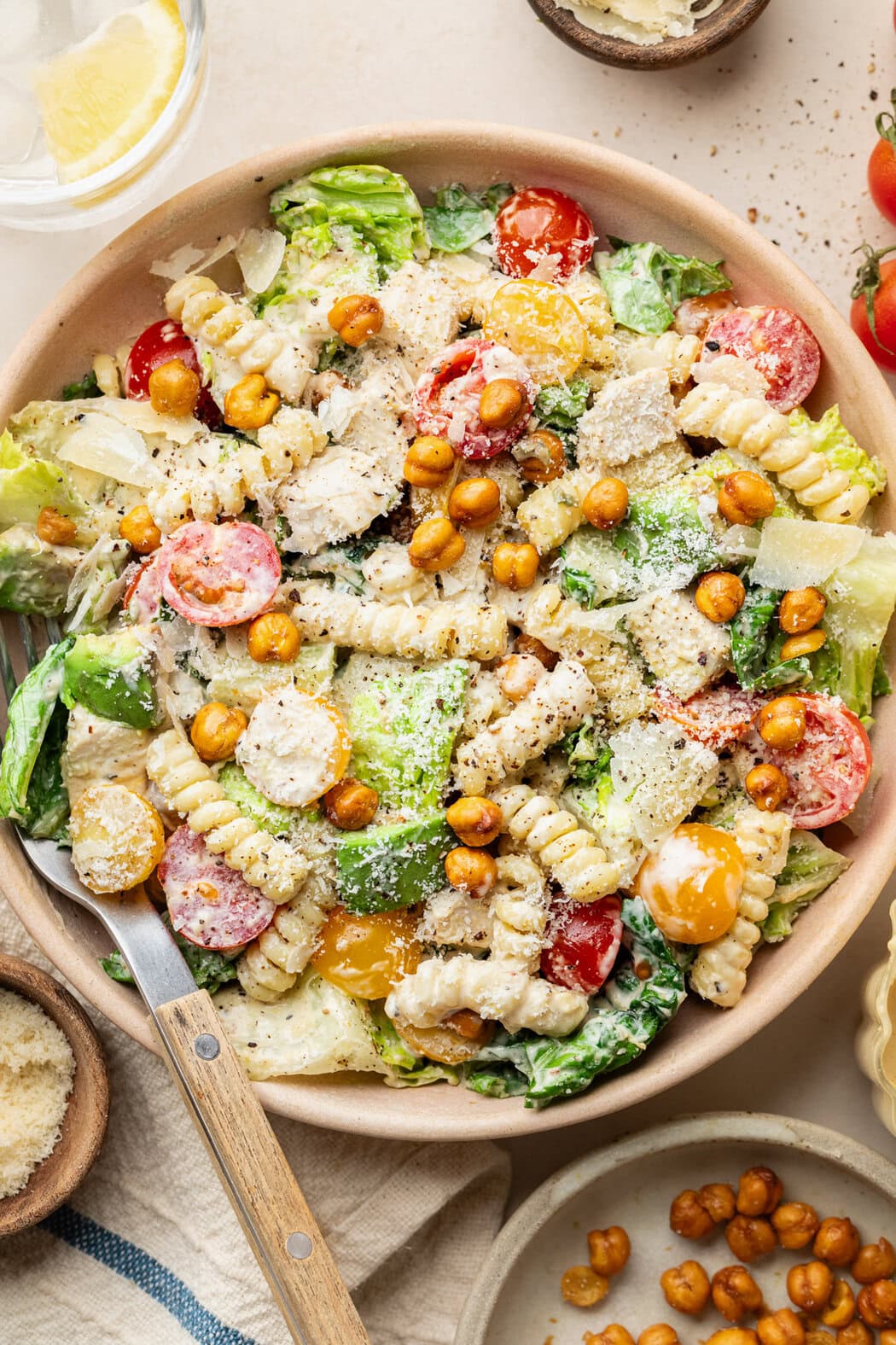 Overhead view of a large serving bowl of Chicken Caesar Pasta Salad topped with crunchy roasted chickpeas and fresh parmesan cheese. 
