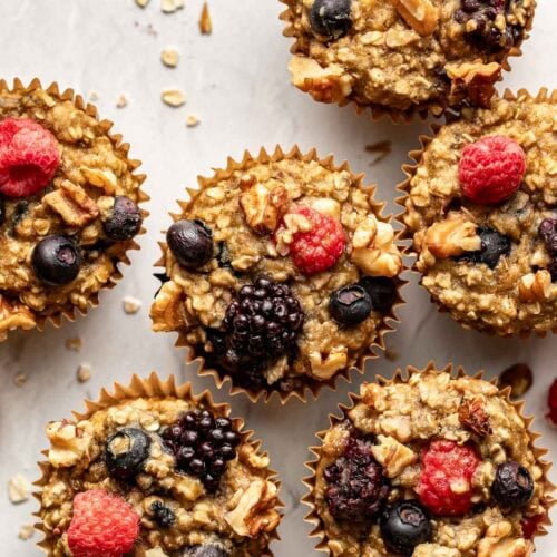 Overhead view mixed berry baked oatmeal muffins on counter topped with fresh berries and walnuts