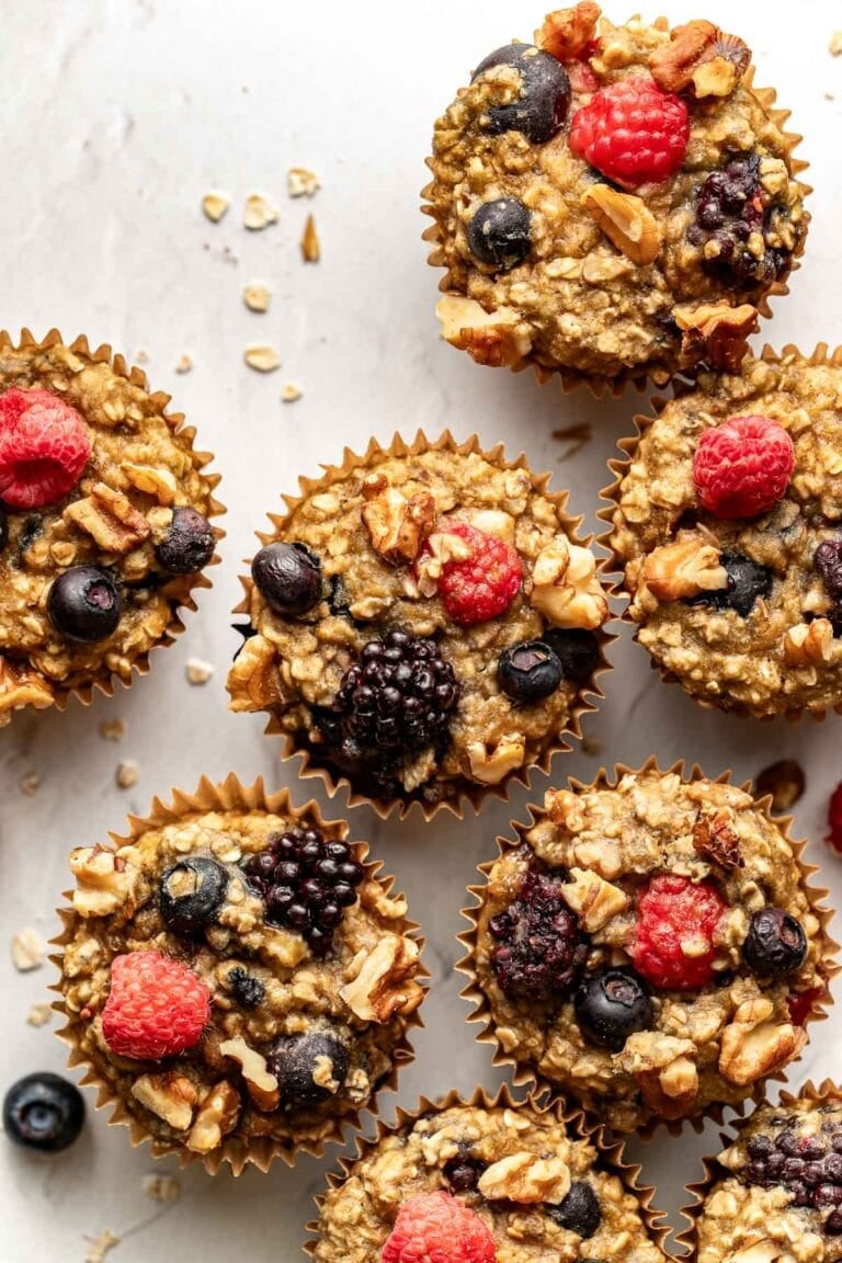 Overhead view of mixed berry muffins topped with colorful berries and walnut pieces. 