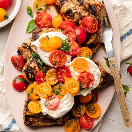 Overhead view platter filled with grilled chicken caprese with melty burrata on top