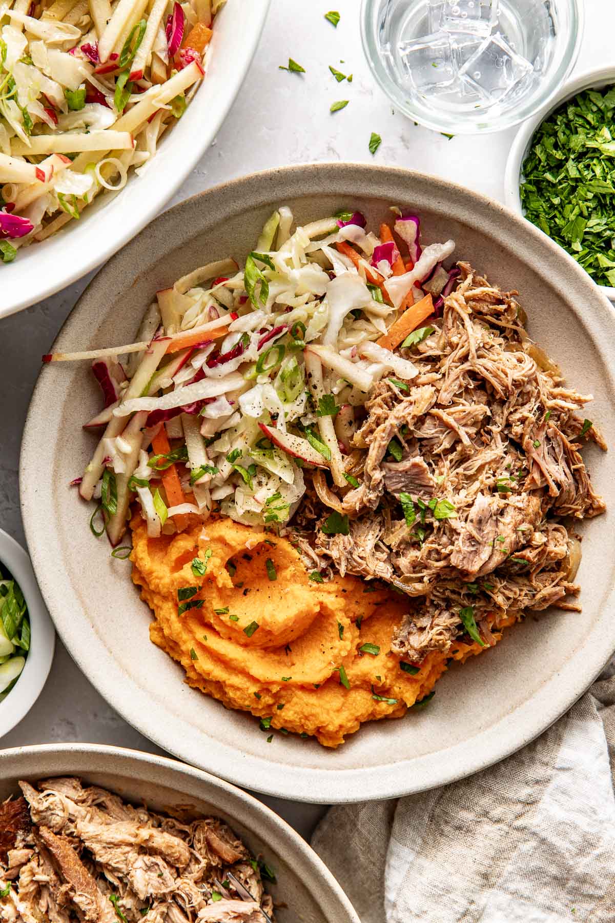 Overhead view of a white plate filled with pulled pork, mashed sweet potatoes, and colorful Apple Slaw. 