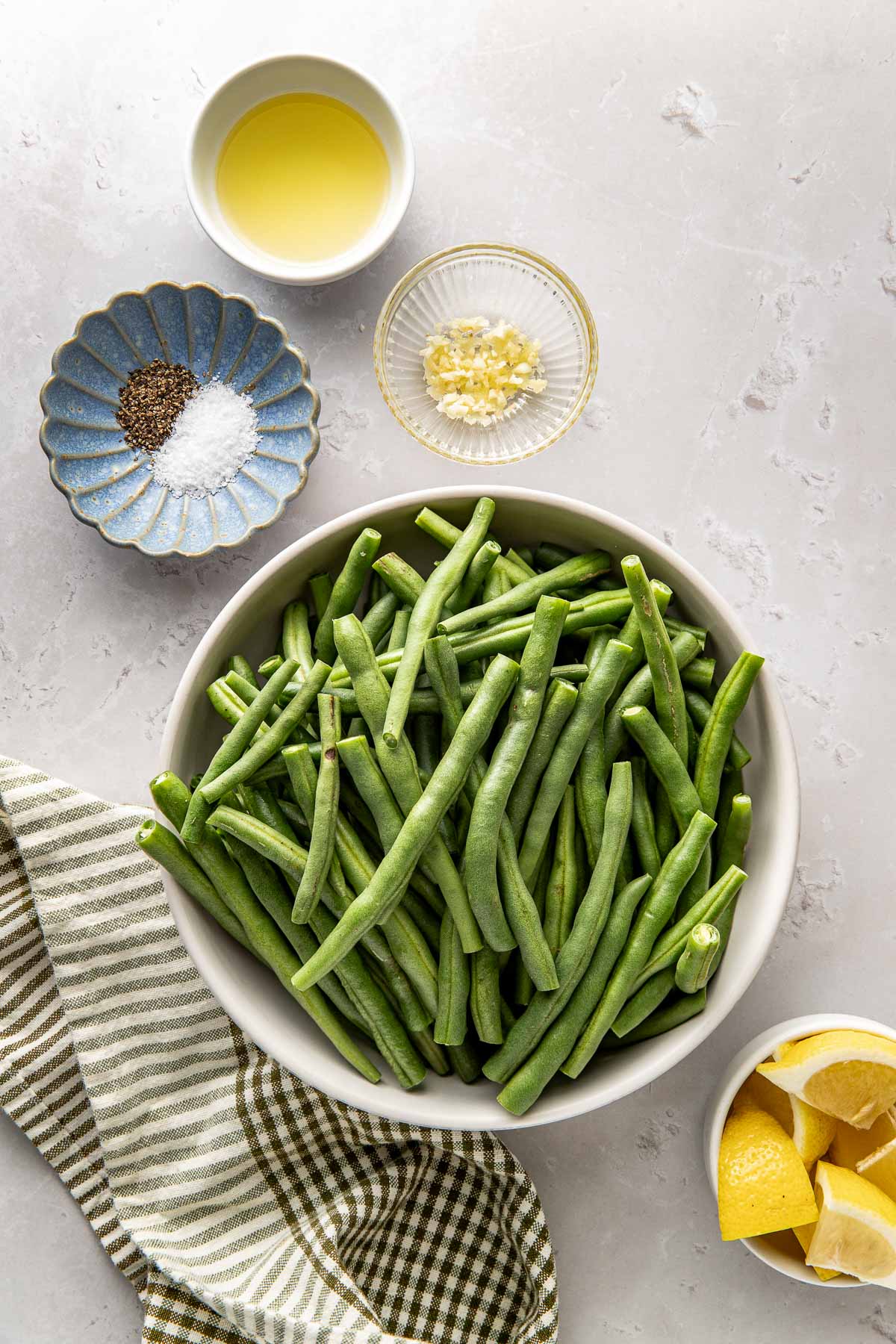 Overhead view of a variety of ingredients for air fryer green beans including garlic and lemon wedges. 
