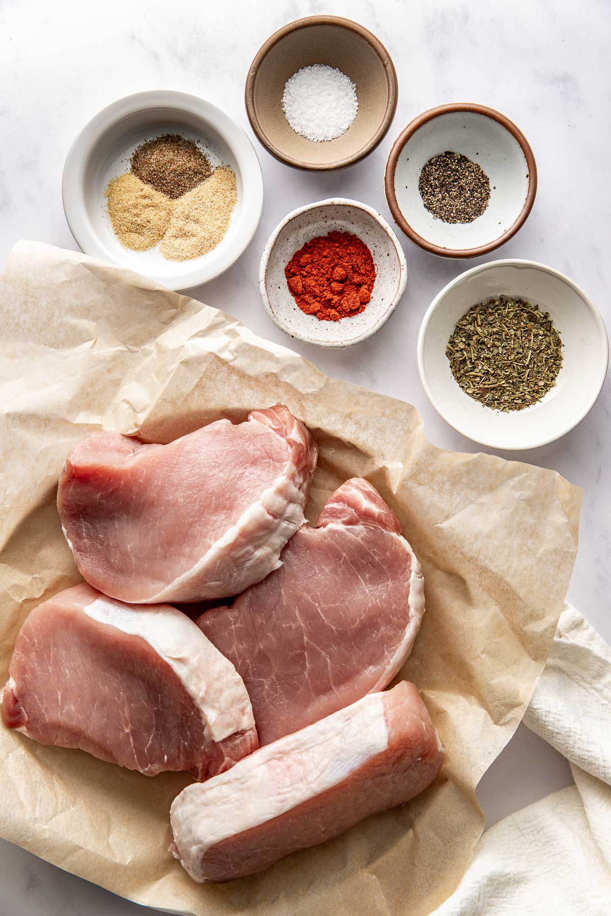 Overhead view of a variety of ingredients for air fryer pork chops in different sized bowls. 