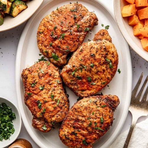 Overhead view of a platter filled with freshly roasted porkchops showing crisp outside and perfectly seasoned.