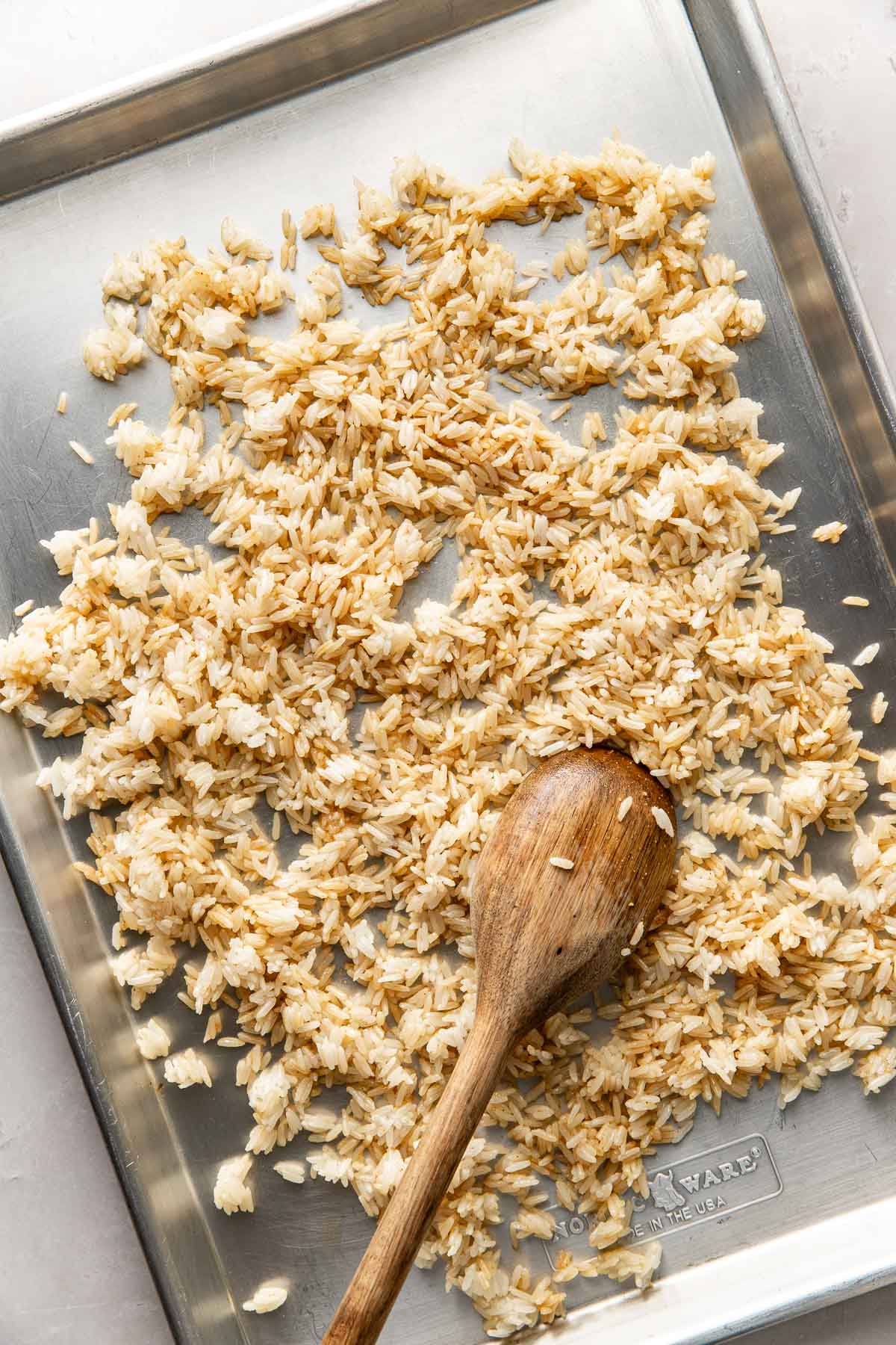 Overhead view of a sheet pan filled with rice spread across the surface. 